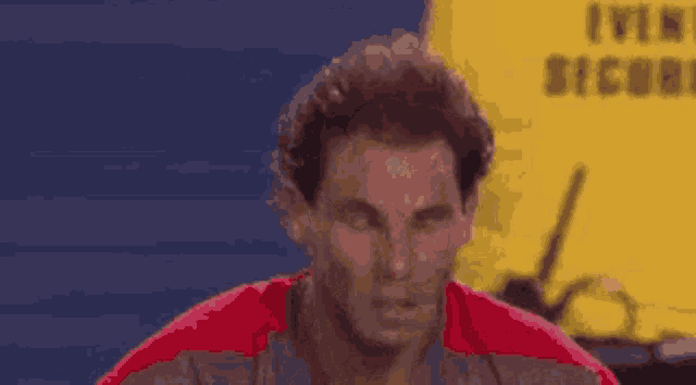 a man in a red shirt is looking at the camera .