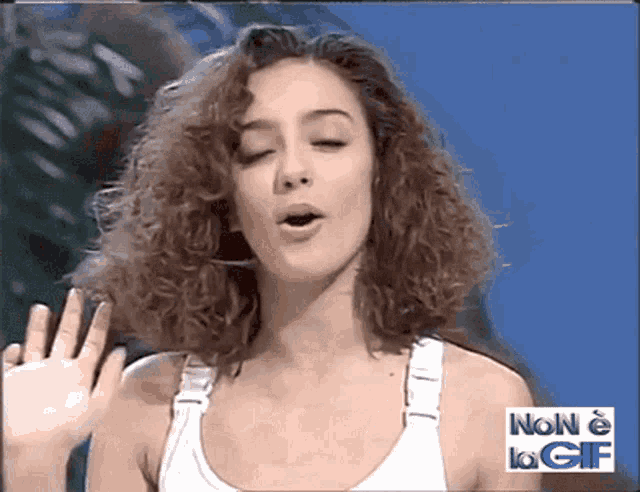 a woman in a white tank top with the words non e la gif behind her