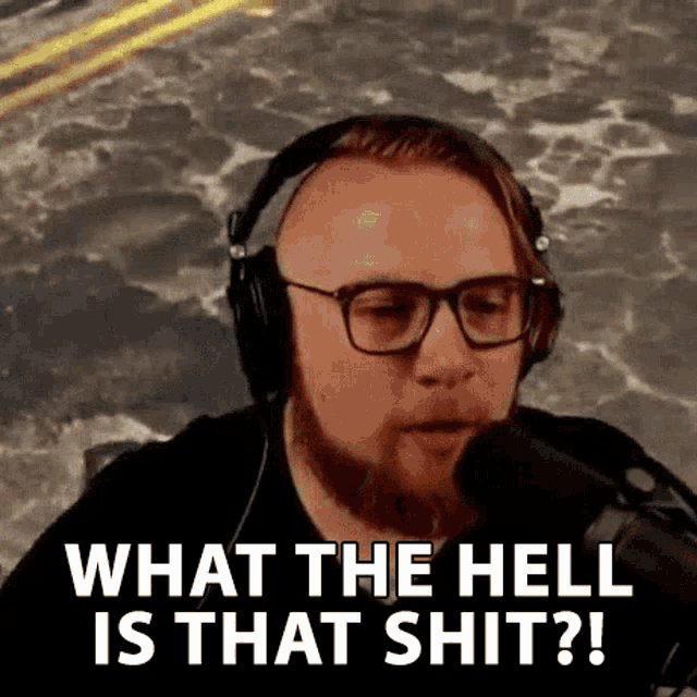a man with glasses and headphones is talking into a microphone and saying `` what the hell is that shit ? ''