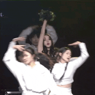 a group of people are dancing on a stage with one woman holding up her arm
