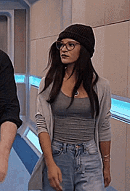 a woman wearing a beanie and glasses is walking with a man .