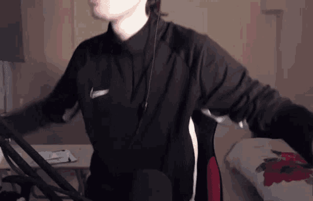 a man wearing headphones is standing in front of a microphone in a room .