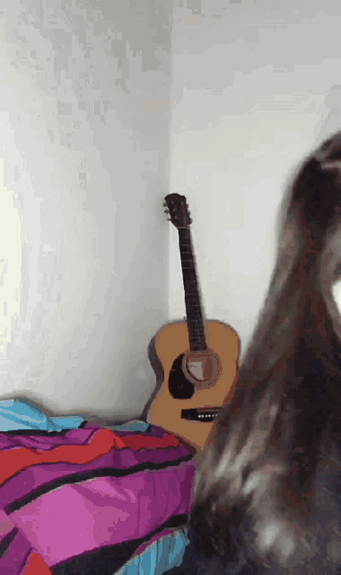 a guitar is sitting in the corner of a bedroom next to a bed