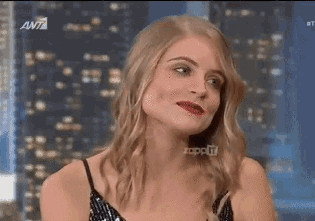 a woman is smiling and making a funny face while sitting on a stage .