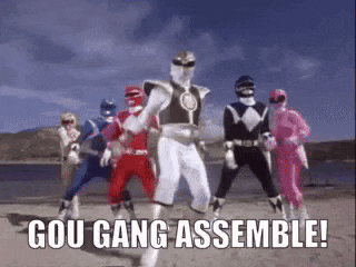 a group of power rangers are standing next to each other on the beach .