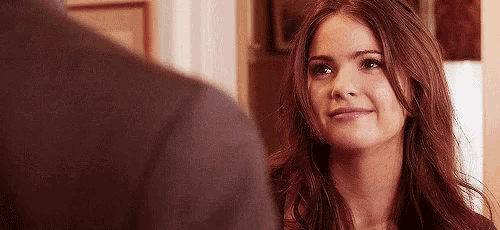 a woman is smiling at a man in a suit while looking at him .