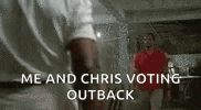 a man in a red shirt is standing next to another man in a white shirt and says `` me and chris voting outback ''
