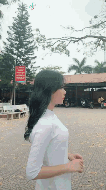 a girl in a white dress is standing in front of a building with a sign that says " no smoking "