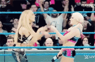 two women are wrestling in a ring with a crowd in the background .