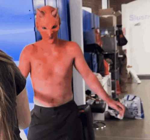 a shirtless man in a devil mask is standing in front of a sign that says store
