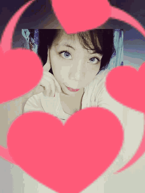 a girl is surrounded by pink hearts and looks at the camera