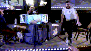 a man in a white shirt is standing on a stage in front of a box that says converse