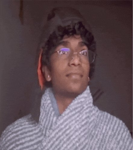 a young man wearing glasses and a striped sweater is looking at the camera .
