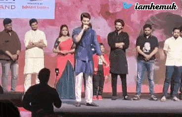 a group of people standing on a stage with a man standing in front of them holding a microphone .