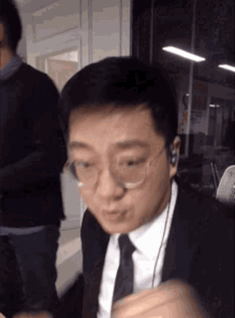 a man in a suit and tie is wearing headphones and glasses