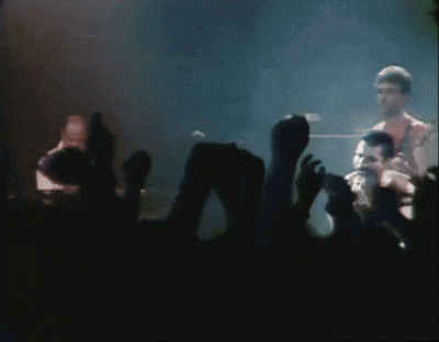 a man is singing into a microphone in front of a crowd at a concert