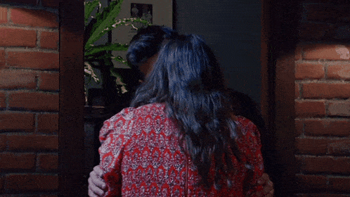 a man in a blue shirt kisses a woman in a red dress