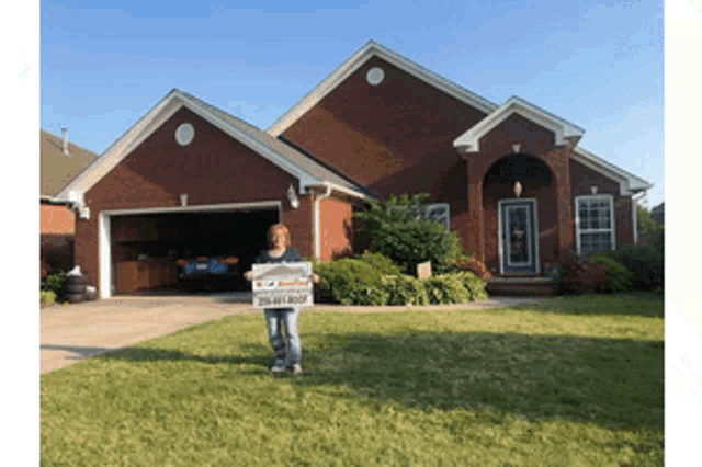 a woman stands in front of a brick house holding a sign that says 305-441-roof