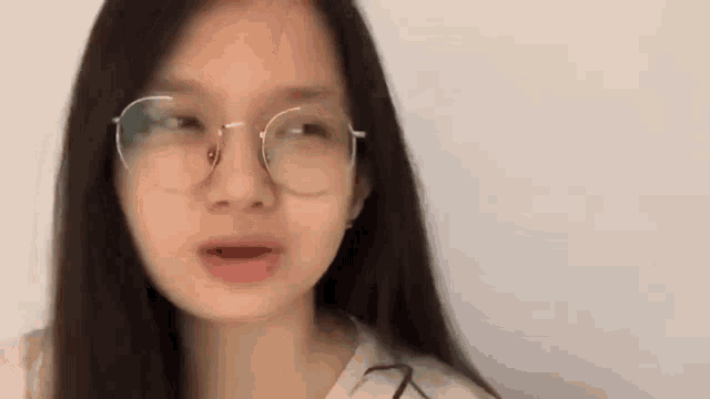 a close up of a woman wearing glasses and a white shirt .
