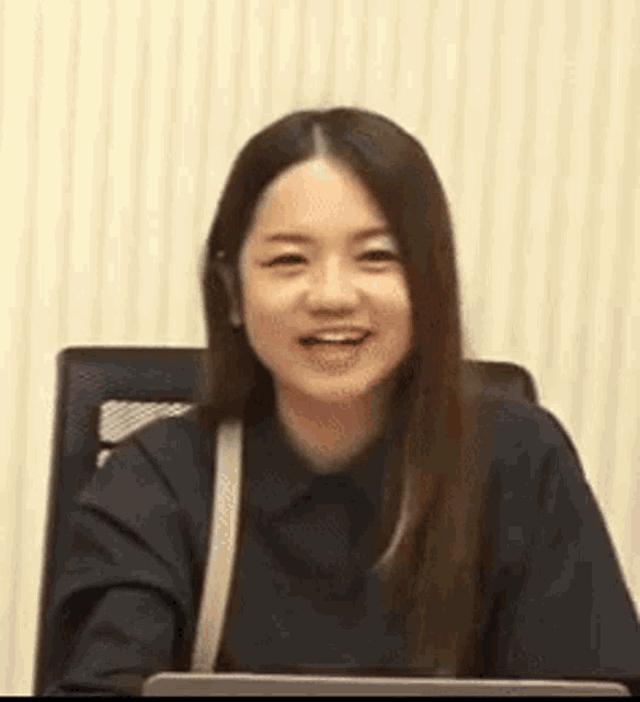 a woman is sitting in a chair and smiling while looking at the camera .