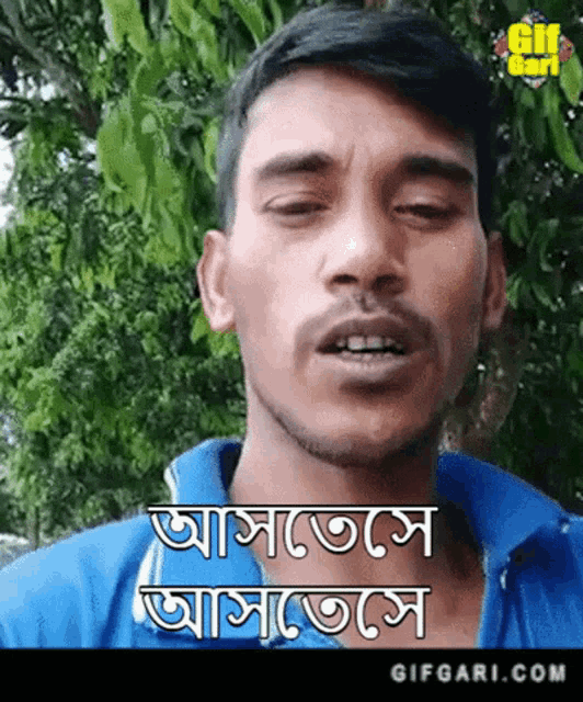 a man with a beard is wearing a blue shirt and says ' gifgari.com ' on the bottom