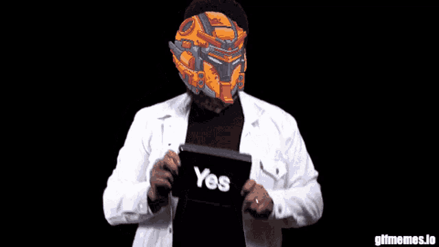 a man wearing a robotic helmet holds a tablet that says yes