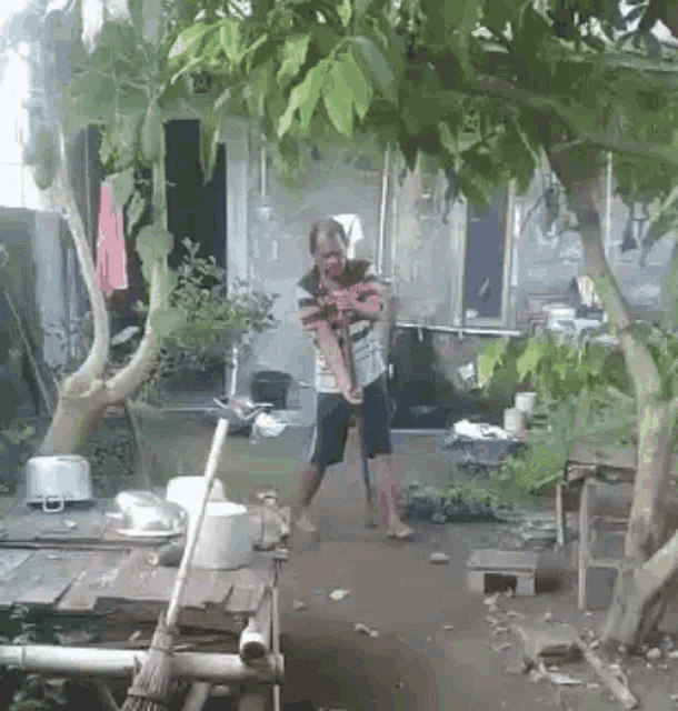 a man is standing in front of a house with a broom in his hand .