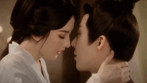 a man and a woman are kissing in front of a mirror .