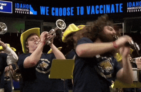 a group of people are playing instruments in front of a sign that says we choose to vaccinate