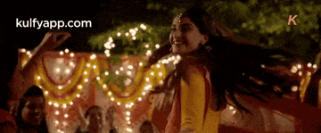 a woman in a yellow dress is dancing in front of a crowd at a party .