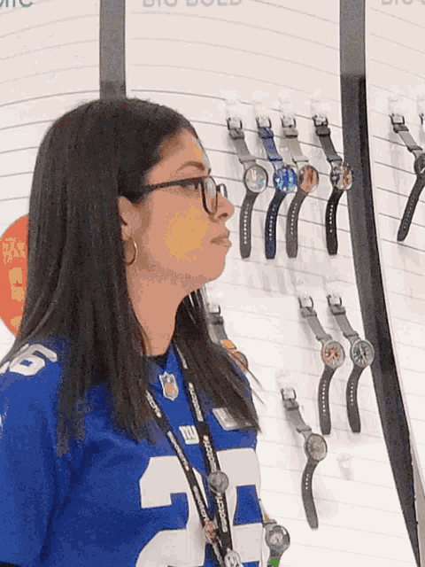 a woman wearing a blue jersey with the number 22 on it stands in front of a wall of watches
