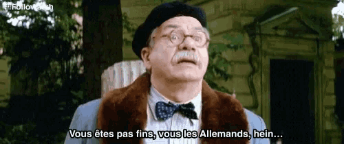 a man in a beret and bow tie is talking in french