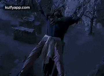 a man is standing on top of a rock with his arms outstretched in the air .