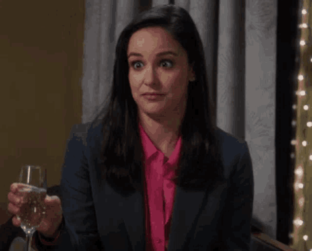 a woman is holding a glass of water and making a funny face .