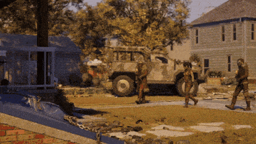 a group of soldiers are walking down a street in front of a military vehicle
