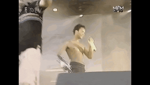a shirtless man is holding a microphone on a stage .