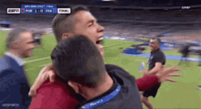 a man wearing a france lanyard is hugging another man on a field