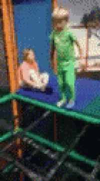 a boy and a girl are playing on a trampoline in a park .