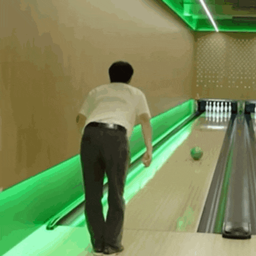 a man is bowling in a bowling alley with green lights
