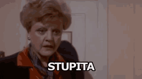 a woman in a suit and scarf is screaming and saying stupida .