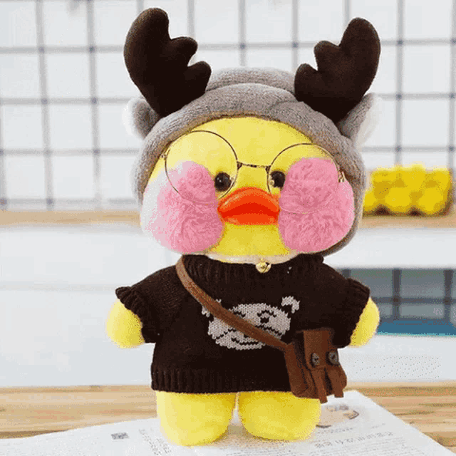 a stuffed yellow duck wearing a sweater and glasses