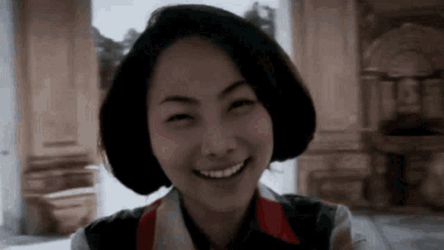 a close up of a woman smiling in a room with a blurred background .