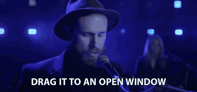 a man singing into a microphone with the words drag it to an open window next to him