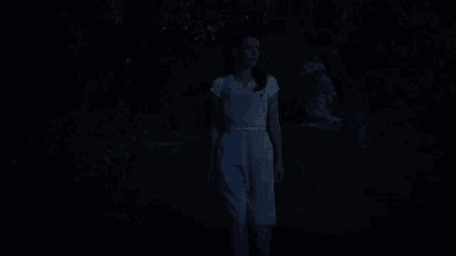 a woman in overalls is standing in the dark