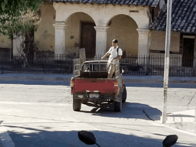 a man is standing in the back of a red pickup truck with a license plate that says ' a ' on it