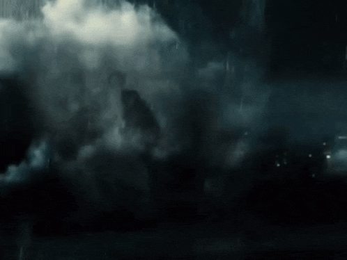 a man in a cape is walking through a foggy area .