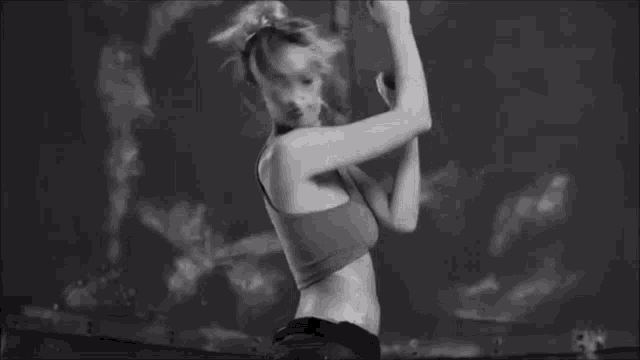 a woman in a crop top is dancing in a black and white photo .