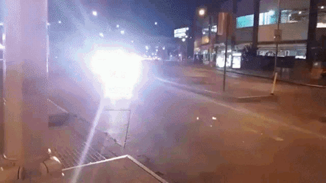 a car is driving down a street at night and the lights are shining brightly .