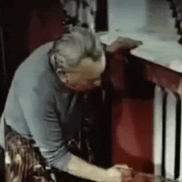 a man in a blue shirt is working on a red table .