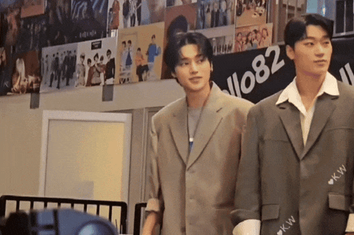 two men are standing next to each other in front of a sign that says ' 082 ' on it